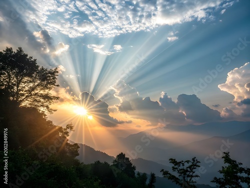 Sunrise over misty mountain range with dramatic sunbeams and trees