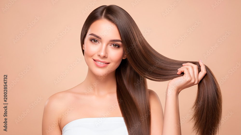 Naklejka premium Beautiful woman with long, healthy, shiny brown hair smiling and touching her hair