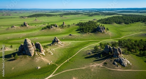 Scenic Aerial View of Rocky Outcrops in a Lush Green Meadow Under a Clear Blue Sky.