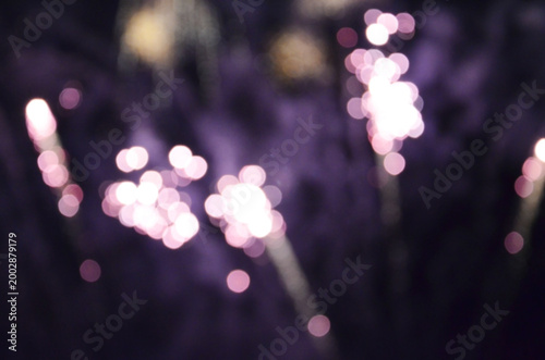 Blurred lights resembling fireworks or sparklers against a dark purple backdrop