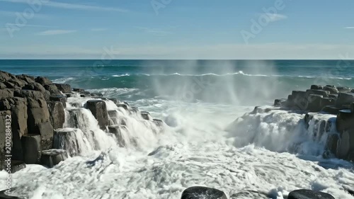 Powerful ocean waves crashing against unique basalt columns at Giant's Causeway, Northern Ireland