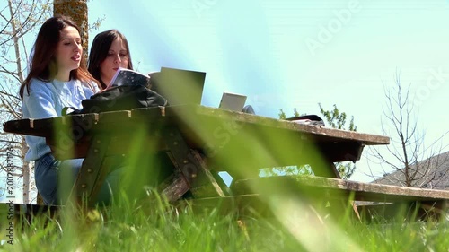 Female students collaborating on a homework assignment outdoors in a park