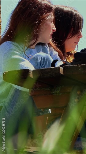 University students talking and studying together outdoors at a campus park table