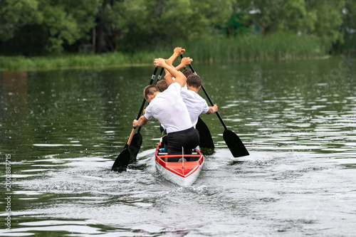 Foto Young four athletes canoeist paddling on open water
