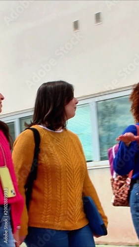 Happy female students walking and talking together outside the university campus