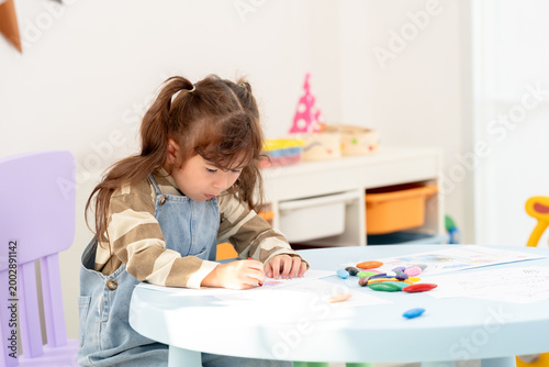 Obraz na płótnie Asian toddler daughter concentrates drawing line on paper, single mother teaching kids at home, home schooling activity, parent child trust, art therapy and expression, weekend indoor lifestyle