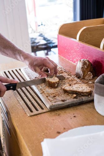 Obraz na plátně Découpe de pain sur une planche en bois dans un restaurant