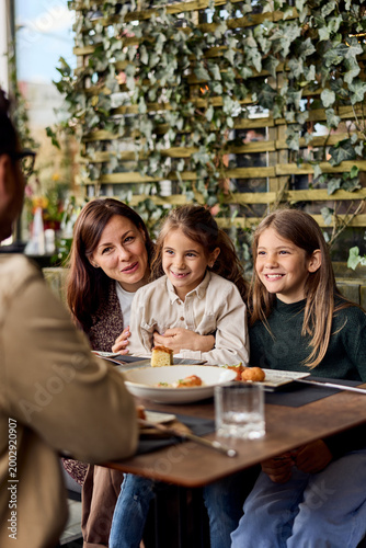 Mother and Two Daughters Smiling Together Over Lunch at a Cafe Terrace During Family Brunch