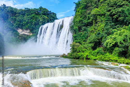 Powerful Huangguoshu Waterfall rushing into river basin in Anshun, China, with lush green vegetation