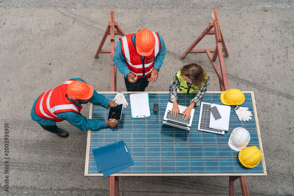 Fototapeta premium Construction worker solar panel team helmet laptop table safety planning inspection