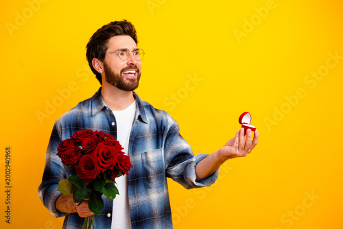 Fotografie Smiling man holding red roses and offering an engagement ring in a romantic prop