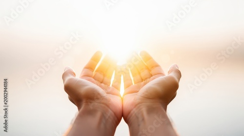 Two hands gently cupping bright sunlight, symbolizing hope, warmth, and energy against a soft, glowing background.