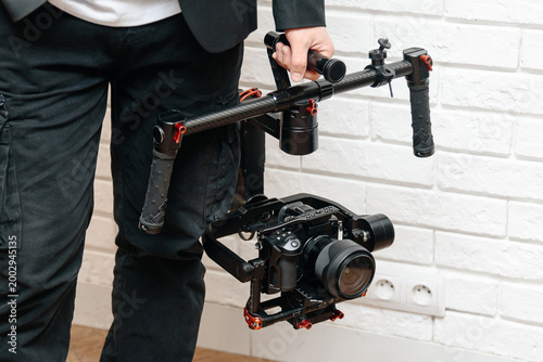videographer working indoors with video camera set on steadycam in hands, cameraman at work