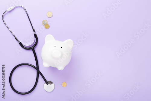 Piggy bank with stethoscope on color background, top view. Healthcare savings concept