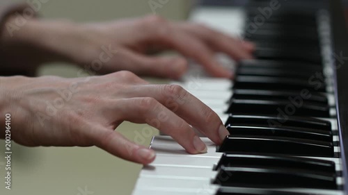 female pianist hands on black and white synthesizer keyboard, close-up view, young woman playing piano, professional musician