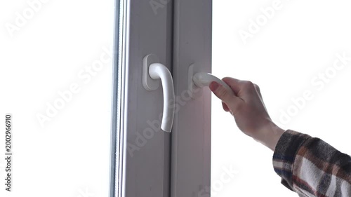 woman hand closing white plastic window by handle, in house or apartment or office, young caucasian girl in warm plaid shirt