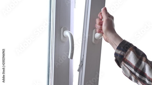 woman hand opening white plastic window by handle, in house or apartment or office, young caucasian girl in warm plaid shirt