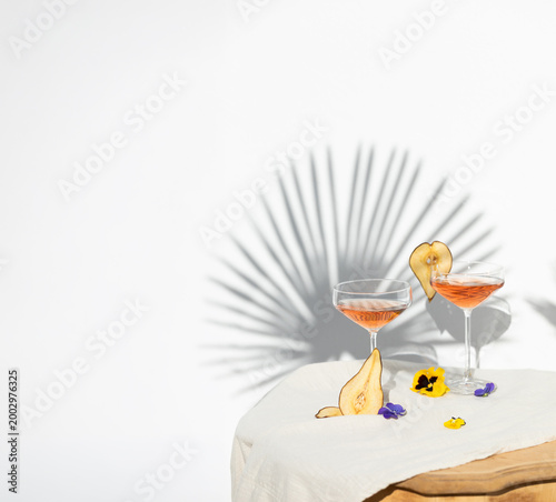 Two rose wine glasses with summer cocktails and dried fruit appetizers