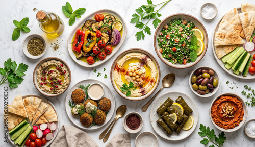 Flat lay of traditional Middle Eastern mezze spread with hummus tabbouleh pita bread and grilled vegetables on a marble table