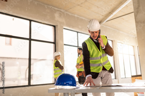 Photos Workers discuss project plans in a construction site office during the day