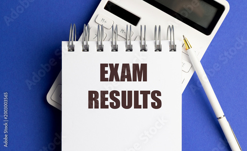 Exam results concept with notebook, calculator and pen on blue background, education assessment 