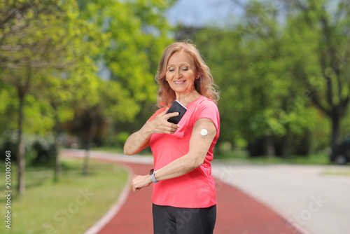 Cuadro en lienzo Mature woman scanning a glucose sensor with her smartphone