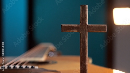 Φωτογραφία Wooden cross standing in the foreground with an acoustic guitar in the soft focu