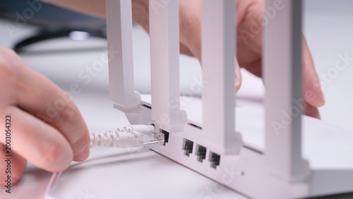 Bild auf Leinwand Person hand connecting a white ethernet cable into the port of a modern white wi