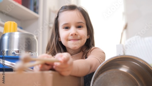 Photography Happy little girl smiling at the camera, holding wooden spoons and playing impro