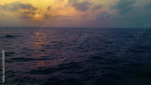 Golden sunset over the open ocean with dramatic clouds and gentle waves