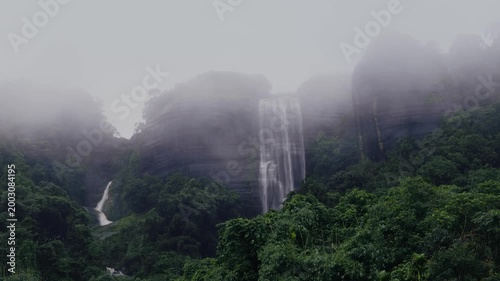 Misty waterfall cascading through lush rainforest cliffs in Meghalaya during monsoon season