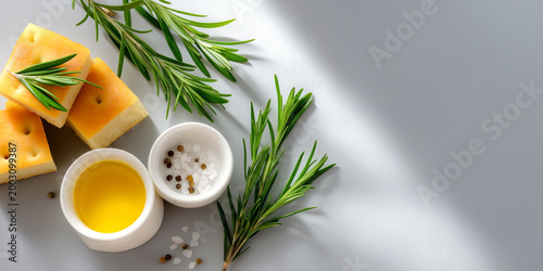 Flat lay with rosemary herbs, olive oil, sea salt and focaccia bread on light background, fresh cooking ingredients and mediterranean cuisine concept