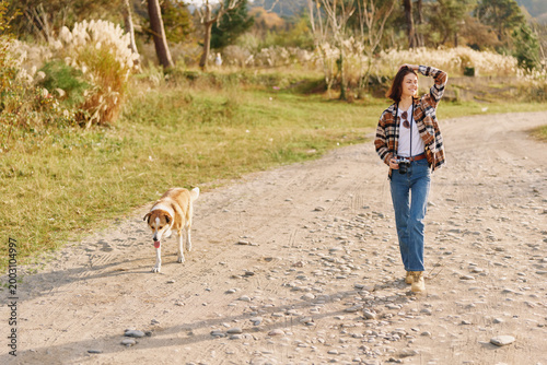 Tableau sur toile Woman walking with a dog along a dusty rural path, enjoying outdoors and nature,