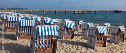 Strandkörbe on Rugen beach lined in blue and white stripes facing Baltic Sea pier