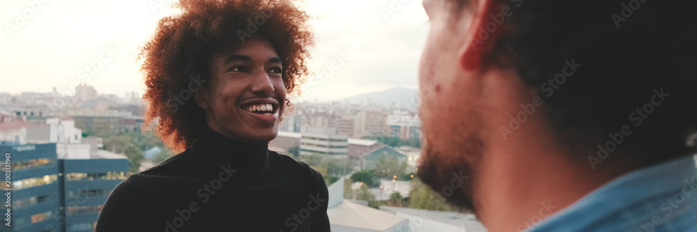 Obraz premium Close-up of young mans talking, in the background on the terrace his friends. Panoramic. Panoramic