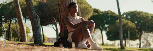 Young woman in casual clothes chilling outdoors among the trees in the park, relaxing in an urban environment and mental health concept. Panoramic. Panoramic
