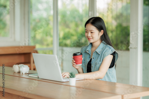 Conceptual image of financial growth: A young professional using a laptop with a piggy bank nearby, representing future wealth.