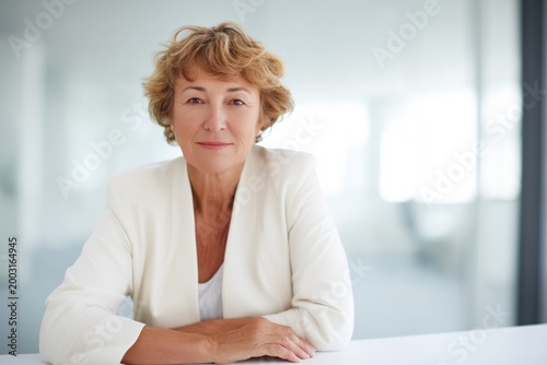 Confident mature business woman executive sitting at desk in office looking at camera, professional female manager entrepreneur portrait for corporate website and leadership profile