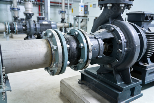 Fotografie Industrial worker tightening bolts on a large pump system in a factory setting