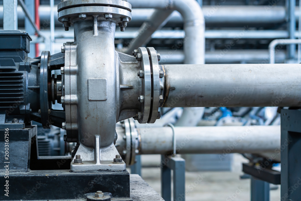 Obraz premium Industrial worker using a wrench to tighten bolts on a large metal pipe system