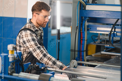 Fotografie Worker operating machine producing polyethylene plastic bag