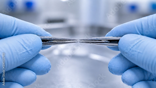 Close Up of Gloved Hands Holding Surgical Instrument for Inspection and Sterile Preparation in Clinical Setting