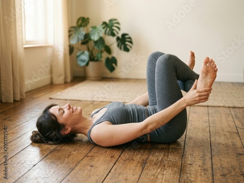 Young Woman Practicing Yoga at Home on Wooden Floor with Peaceful Expression and Relaxed Pose