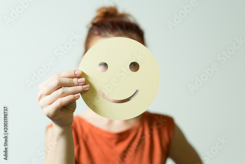 Quadro em tela Person hiding their face behind a yellow smiley face cutout