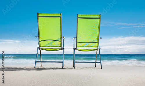 Zwei grüne Stühle am Strand