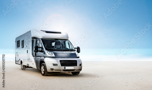Wohnmobil am Strand vor blauem Himmel