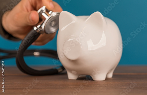 Checking savings and financial health. Piggy bank getting a medical checkup with a stethoscope. Inve