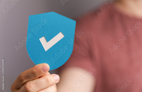 Hand holding a blue shield ...