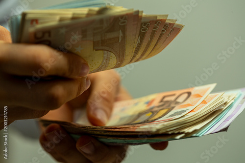 Photos Close-up of hands meticulously counting a fan of euro banknotes