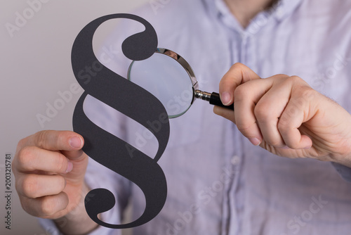 Fotografía Person examining paragraph symbol with magnifying glass for legal research